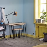 Small home office with FRIDNÄS nesting tables, black metal lamp, blue wall, and yellow accents.