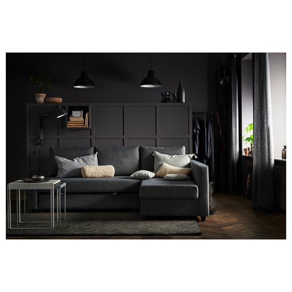 Modern dark living room with dark grey convertible sofa, pillows, and black storage cabinet.
