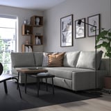 Modern living room with FRIHETEN sofa-bed, art, coffee table, shelves, lamp.