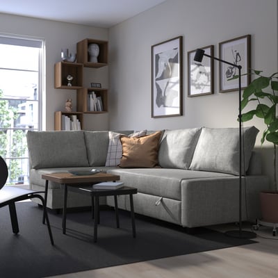 Modern living room with FRIHETEN sofa-bed, art, coffee table, shelves, lamp.