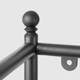 Close-up of sturdy, matte black metal fixture, showcasing round decorative top, robust joint, and attached metal plate with hole.