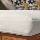 Close-up of outdoor cushion on wood, white checkered fabric, showing quality material and stitching.