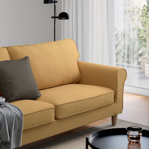 Modern yellow GÄLLTOFTA loveseat by large window.