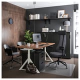 Modern office workspace with GALANT desk, black chairs, wooden accents, and glass partition.
