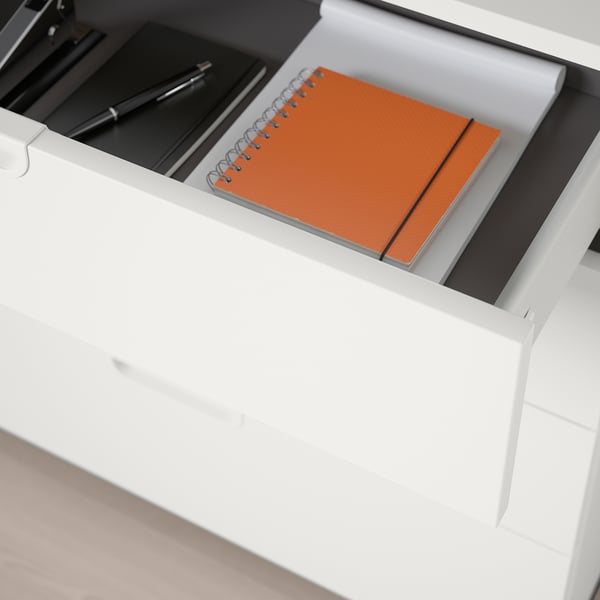 Open office drawer with notebook, pen, and flat accessories, part of a storage unit.