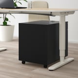 Black rolling storage unit under adjustable desk, featuring combination lock and durable design.