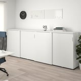 White GALANT office cabinet with sliding doors, plants, books, blue chair, wooden floor.