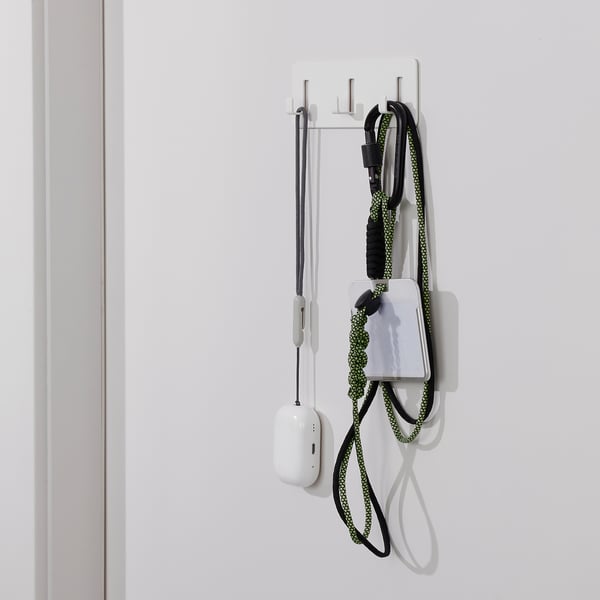 Wall-mounted organizer with 3 hooks holding charging cables and gadgets.