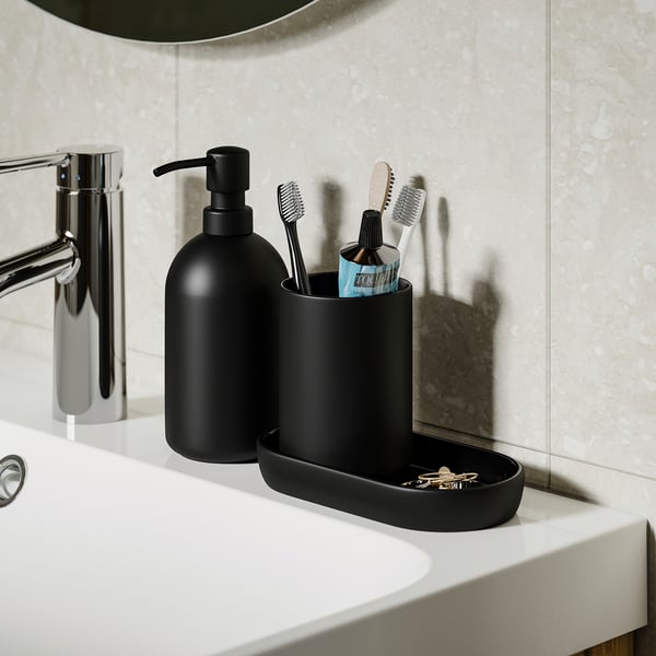 Modern bathroom set: soap dispenser, toothbrush holder, and tray on white sink. Soap dispenser and holder by GANSJÖN.