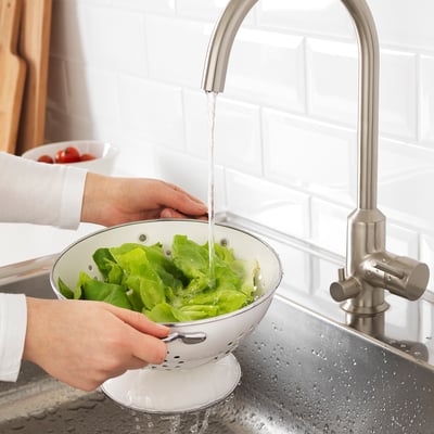 Washing lettuce in colander under kitchen faucet.