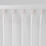 Sheer white curtains hanging, allowing light while offering privacy, with visible curtain hooks at the top.
