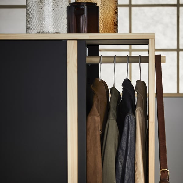 GLAMBERGET wooden coat rack with brown, green, black jackets; textured glass bottles on top.