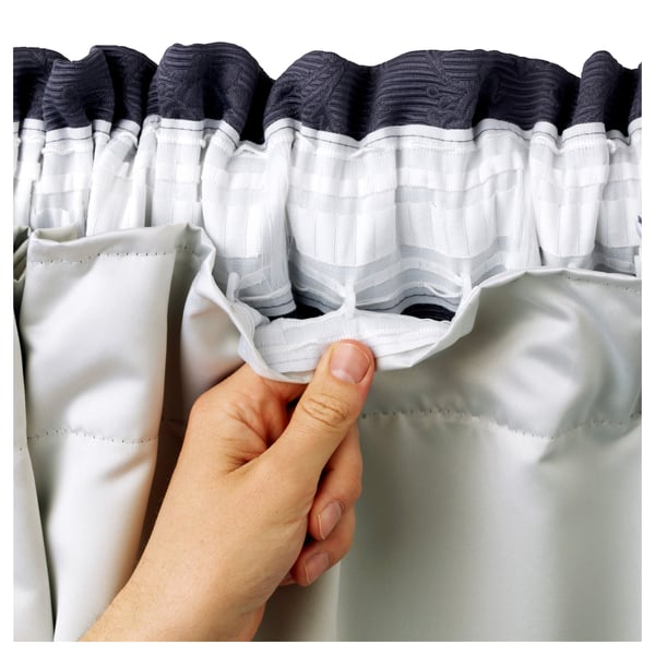 Hand holding gray GLANSNÄVA curtains, showing inner material.