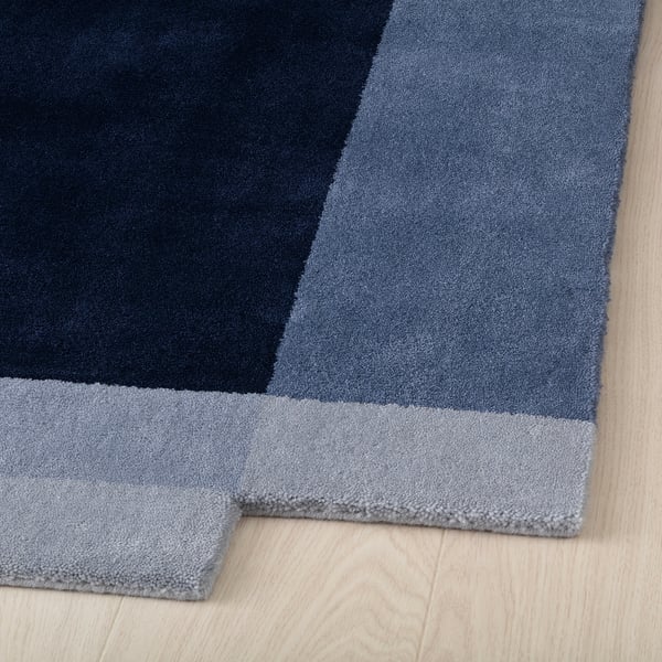 Modern blue area rug, hand-woven, thick wool on wooden floor.