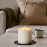 Candle on table creating warm ambiance, next to sofa with pillows and blanket.
