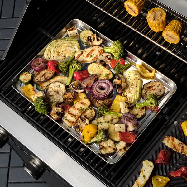GRILLTIDER stainless steel tray filled with grilled vegetables on a bbq grill.