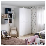A modern bedroom with a white GRIMO wardrobe, featuring clean, bold frames and a beveled edge design.