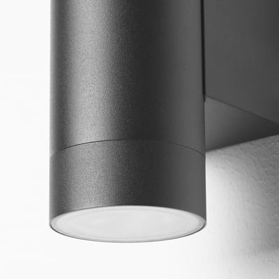 Black wall lamp, modern cylindrical shape, two light sources, outdoor use.