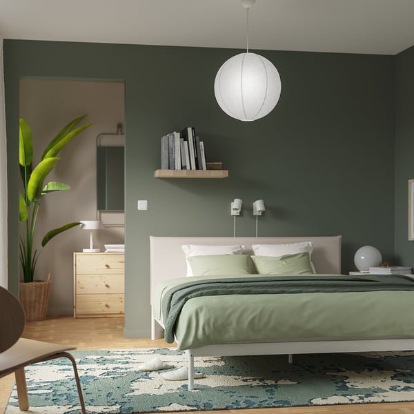 Modern bedroom with GULLSUDARE lamp, green walls, white bed.