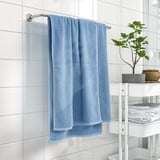 Modern bathroom with blue towels & shelf, emphasizing cleanliness.