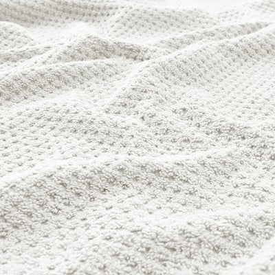 A folded light beige GULVIAL towel, rectangular, with a textured, soft, and fluffy cotton surface.