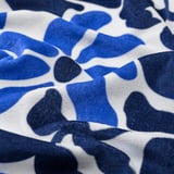 Closeup of a soft, patterned beach towel with blue floral motifs on white cotton.