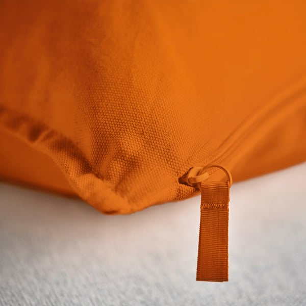 Bright orange cushion cover, close-up of smooth textures and pull zipper, high-quality craftsmanship.