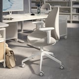 Érèse: modern office setup with light grey ergonomic chair, white desk, monitor, keyboard, mouse, and shelves.