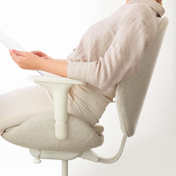Person sits in ergonomic office chair, using laptop; armrests and backrest visible.