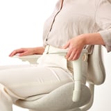 Woman adjusting ergonomic office chair armrests; demonstration of height and width adjustable feature.