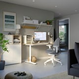 Home office setup with HATTEFJÄLL chair, white desk, shelves, computer, and plants.
