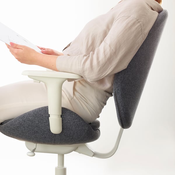 Woman sitting in ergonomic office chair, adjusting armrests.