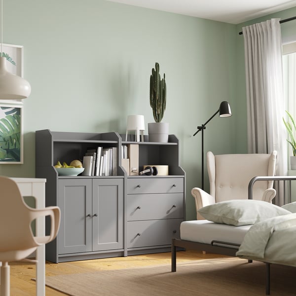 Modern light grey living space with grey HAUGA furniture, a large cactus plant, and a cozy armchair near a window with sheer curtains.
