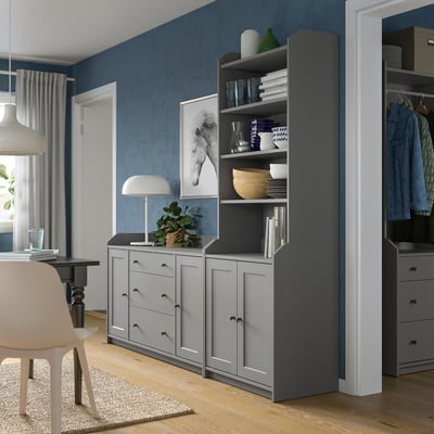 Modern living space with blue walls, gray HAUGA storage unit, drawing table, and white chair.