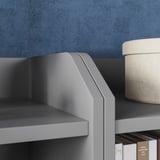 Gray HAUGA storage unit against blue wall, with woven basket on top shelf and books on bottom.