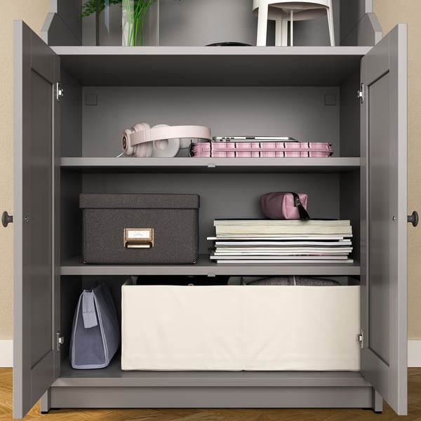 Open storage cabinet with shelves, holding boxes, papers, and bags. Grey color, modern design, wooden material.