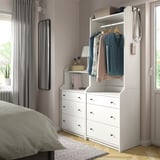 Bedroom with HAUGA white wardrobe and dresser, grey curtains, hanging clothes, mirror, and bed.