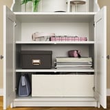 Open white HAUGA storage cabinet, organized with various items like books, bags, and boxes on shelves.