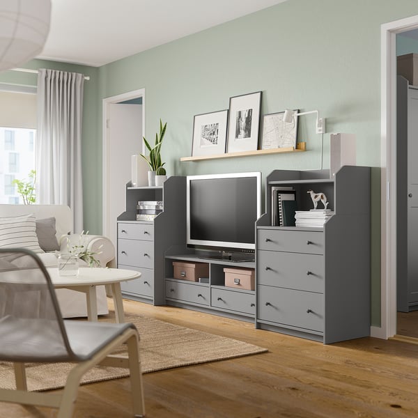 Modern living room with green walls, light wood floors, grey HAUGA storage units, tv, plants, and minimalist decor.