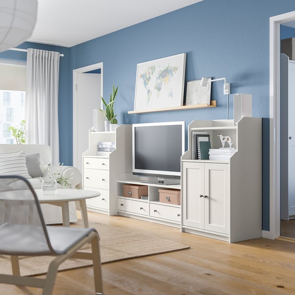 Modern living room with blue walls, white furniture, tv, and decorative items.