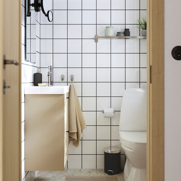 A modern bathroom with a white tiled wall, black accents, and beige towel. Minimalist design with clean lines and contrasting colours.