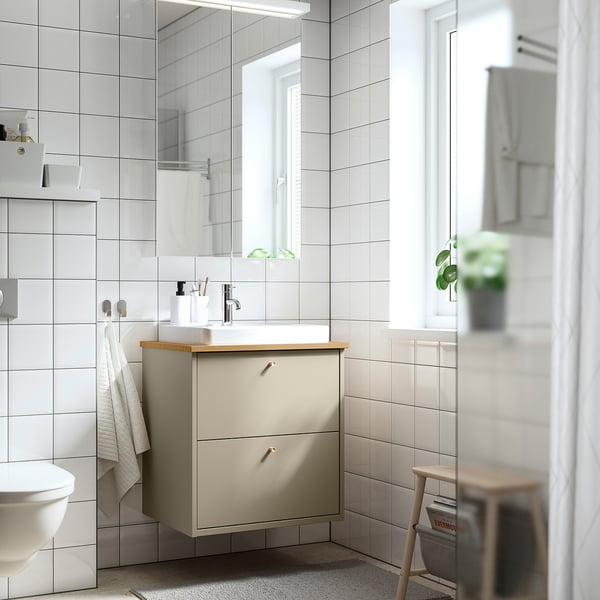 Modern beige bathroom vanity with wood counter, white sink, and mirror.