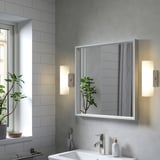 Modern bathroom with wall lamps, mirror, sink, and plant reflection.