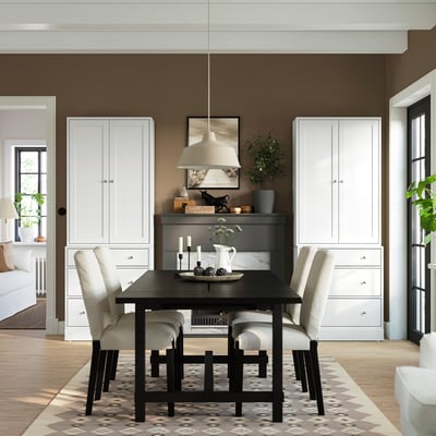 Modern dining room with white HAVSTA cabinet, brown walls, black table, light chairs, and rug.