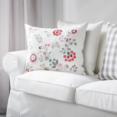 White couch with red flower pillow. Rectangular, removable cover.