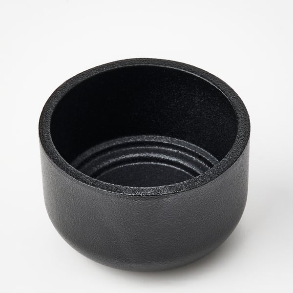 Black, round, metallic candle holder with textured finish.