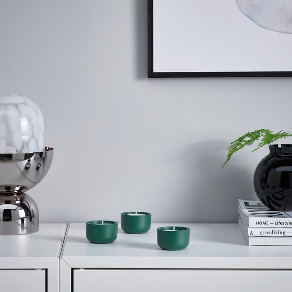 Three green HEDERVÄRD candleholders with magazines and lamp.