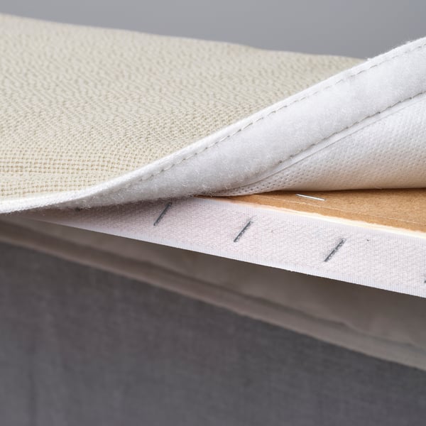 Close-up of a divan beds corner displaying soft, removable mattress cover with stitching and wooden slats underneath.