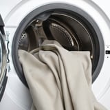 White washing machine open, showing drum and a gray towel inside.