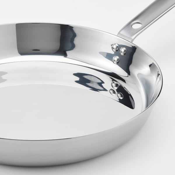 Shiny stainless steel frying pan with a long handle and three rivets. Sleek, polished interior for easy cooking and cleaning.